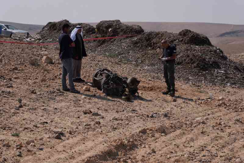 Police and residents inspect the remains of the rocket booster that is believed to have injured Amina